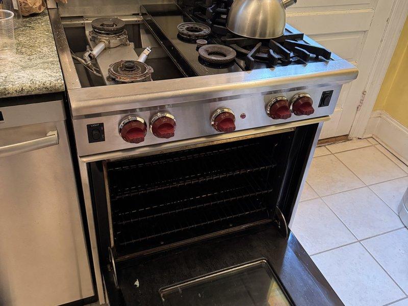 Wolf 30-inch range repair with open oven and tools in NYC kitchen